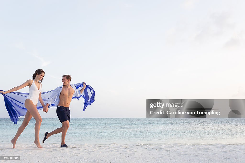 Happy young couple running on beach