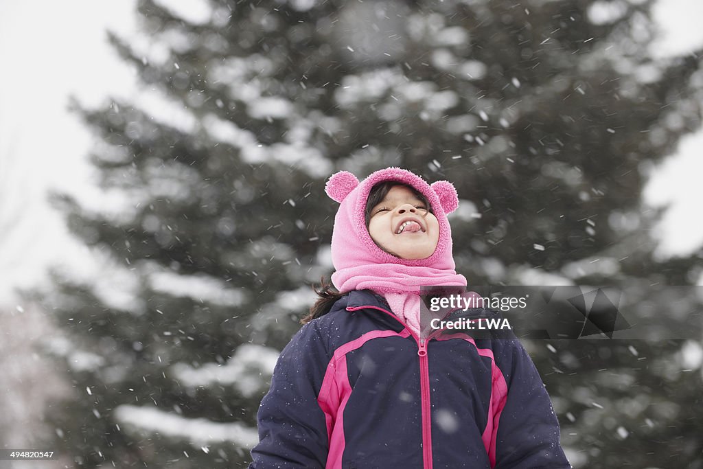 Young girl catching snowflakes on tongue