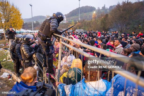 Slovenian policeman goes over a fence to rescue a child pushed by the crowd against the fence, as migrants and refugees wait to cross the...