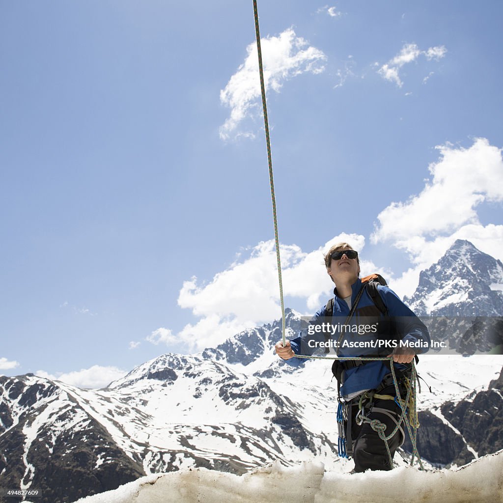 Mountaineer holds rope for teammate above, mtns