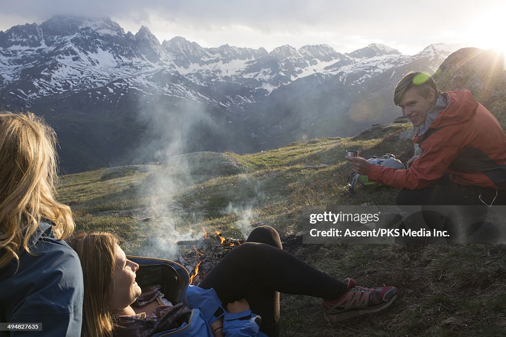 Friends enjoy campfire in mountain meadow