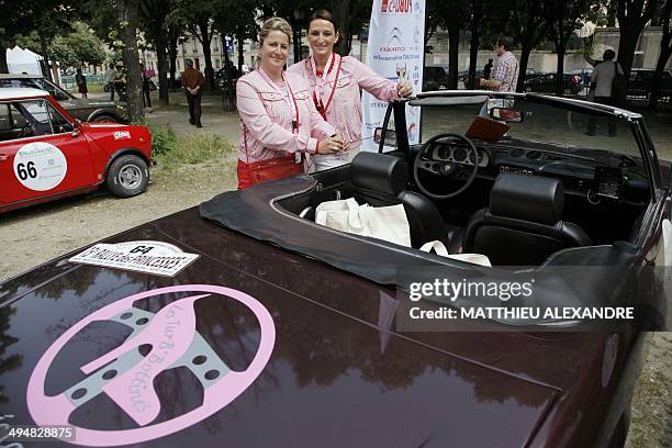 Participants pose next to their vintage car prior to the departure of the 15th edition of the "Rallye des Princesses" on May 31, 2014 in Paris. The...