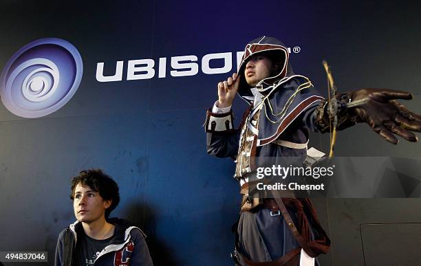 Visitor dressed with a costume of Dorian Arno, a character from "Assassin's Creed Unity" poses in front of a Ubisoft logo during the Paris Games...
