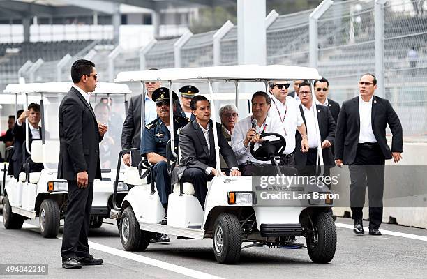 Supremo Bernie Ecclestone arrives in the pit lane with the President of Mexico, Enrique Pena Nieto during previews to the Formula One Grand Prix of...
