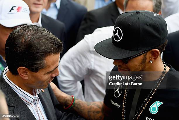 Lewis Hamilton of Great Britain and Mercedes GP greets the President of Mexico, Enrique Pena Nieto in the pit lane during previews to the Formula One...