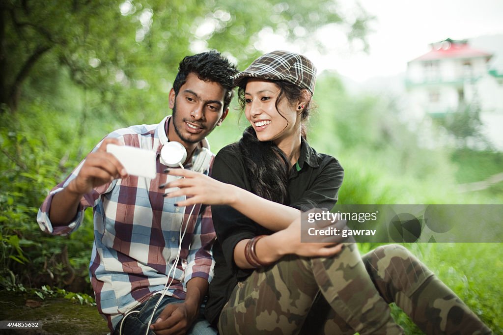 Happy teenage boy and girl of different ethnicity sharing smartphone.