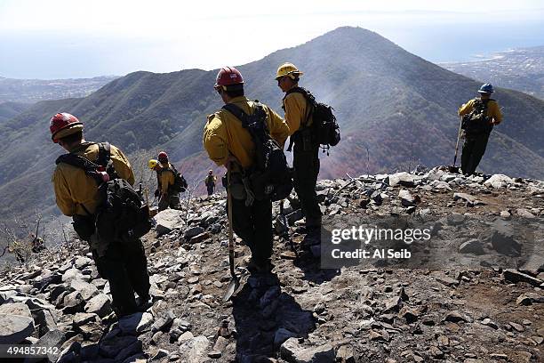 Firefighters from various southern California agencies are ready to get in to position as helicopters drop water during an aerial assault to contain...