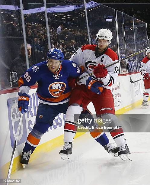 Eric Staal of the Carolina Hurricanes rides Nikolay Kulemin of the New York Islanders into the boards during the third period at the Barclays Center...