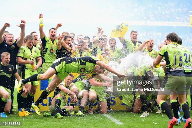 Phil Dowson of Northampton Saints dives in front of his team mates as they celebrate with the trophy after the Aviva Premiership Final between...