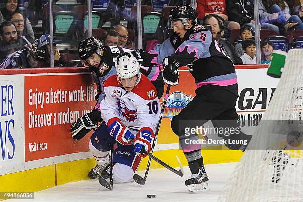 Taylor Sanheim and Connor Rankin of the Calgary Hitmen check Ethan McIndoe of the Spokane Chiefs during a WHL game at Scotiabank Saddledome on...