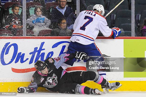 Ben Thomas of the Calgary Hitmen gets checked by Evan Fiala of the Spokane Chiefs during a WHL game at Scotiabank Saddledome on October 29, 2015 in...