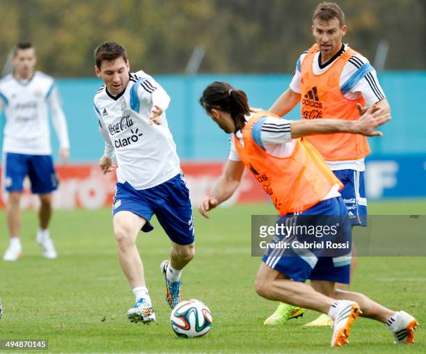 Lionel Messi of Argentina fights for the ball with Martin Demichelis as Hugo Campagnaro looks on during an Argentina training session at Ezeiza...