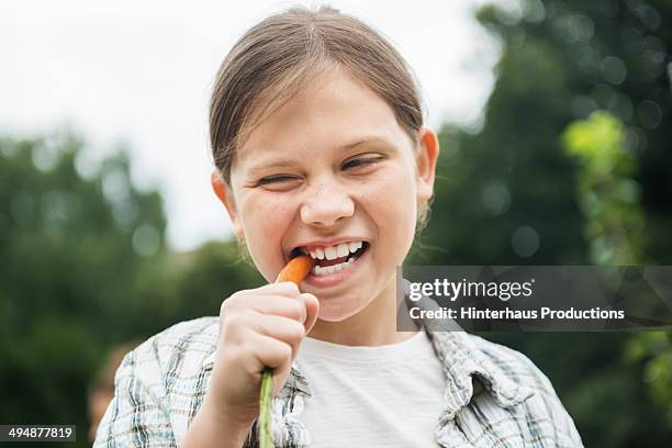 young girl eating fresh carrot - möhre stock-fotos und bilder