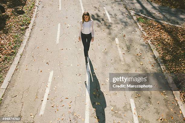 linda garota solitária caminhando pela rua no outono - single lane road - fotografias e filmes do acervo