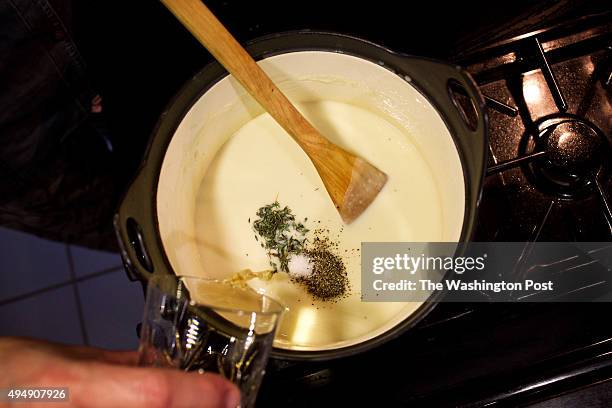 Caterer Anna Saint John's leftover creations - adding salt pepper and sherry to veloute Sauce for potpie photographed in Washington, DC. .