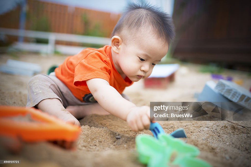 Baby playing in sand with toy