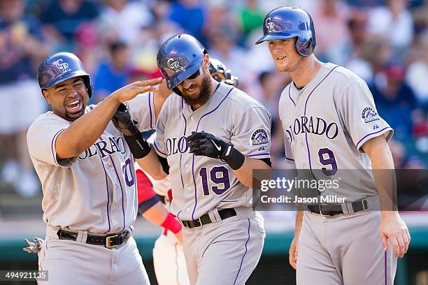 Wilin Rosario and Vinny Castilla celebrate with Charlie Blackmon of the Colorado Rockies after all scored on a home run by Blackmon during the...