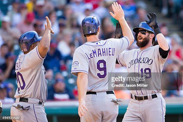 Wilin Rosario and Vinny Castilla celebrate with Charlie Blackmon of the Colorado Rockies after all scored on a home run by Blackmon during the...