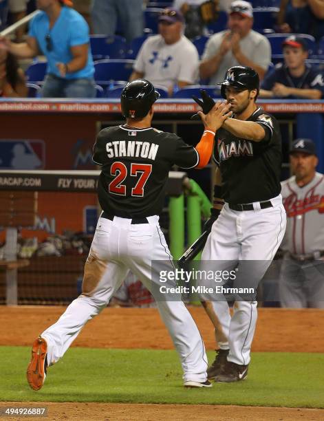 Giancarlo Stanton of the Miami Marlins is congratulated by Garrett Jones after scoring during a game against the Atlanta Braves at Marlins Park on...