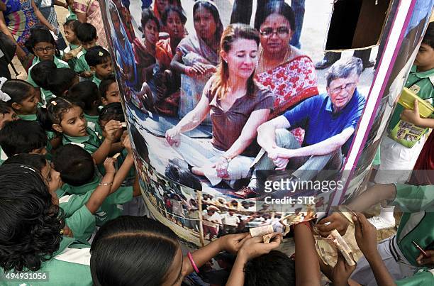Indian schoolchildren donate money for the welfare of the poor into a container featuring a photograph of Microsoft founder and philanthropist Bill...
