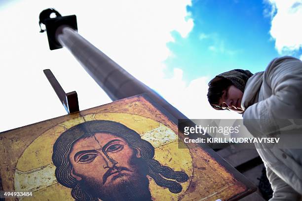 Woman prays next to an icon of Jesus during a rally marking the day of remembrance for the victims of political repression in Moscow on October 30,...