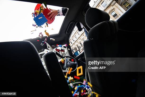 Lego bricks are poured through the sunroof of a BMW 5 series car, used as a receptacle for donations of Lego bricks in the courtyard of the Royal...