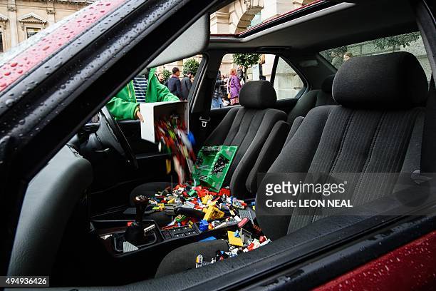 Lego bricks are poured through the open window of a BMW 5 series car, used as a receptacle for donations of Lego bricks in the courtyard of the Royal...
