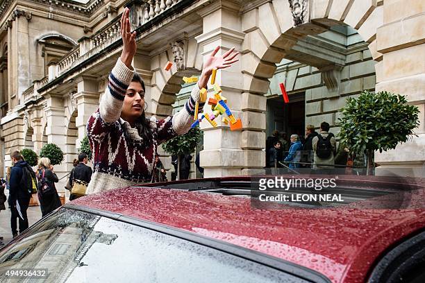 Woman throws Lego bricks into a BMW 5 series car, used as a receptacle for donations of Lego bricks in the courtyard of the Royal Academy in central...
