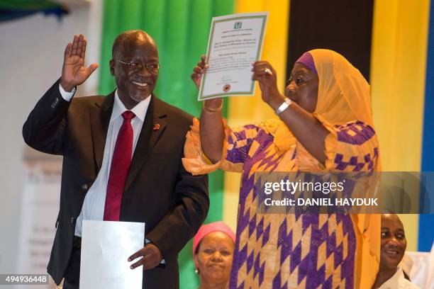 Tanzania's President-elect John Magufuli gestures as Vice President-elect Samia Suluhu holds up a certificate during the official election...