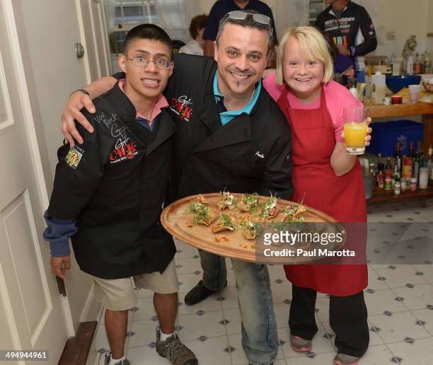Best Buddy Michael Jaxtime-Barry, chef Mark 'Pesto' Canzonetta and Best Buddy Lauren Potter prepare in the kitchen for the after party for the Best...