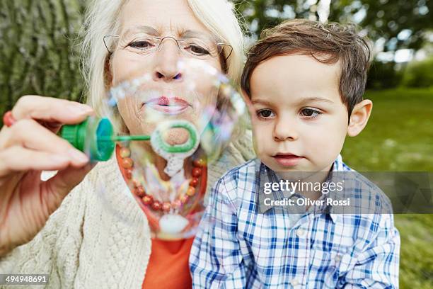 grandmother and grandson blowing soap bubbles - bellenblaas stockfoto's en -beelden