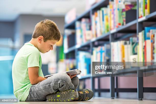schoolboy sitting on the floor in library - public library stock pictures, royalty-free photos & images