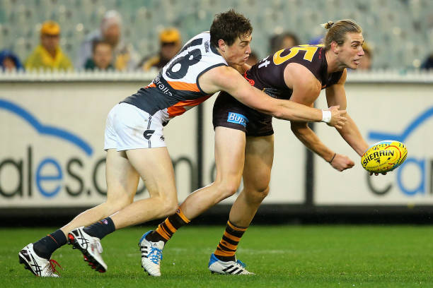 Ryan Schoenmakers of the Hawks handballs whilst being tackled by Jeremy Cameron of the Giants during the round 11 AFL match between the Hawthorn...