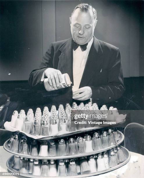 Waiter fills numerous salt and pepper shakers, 1950.