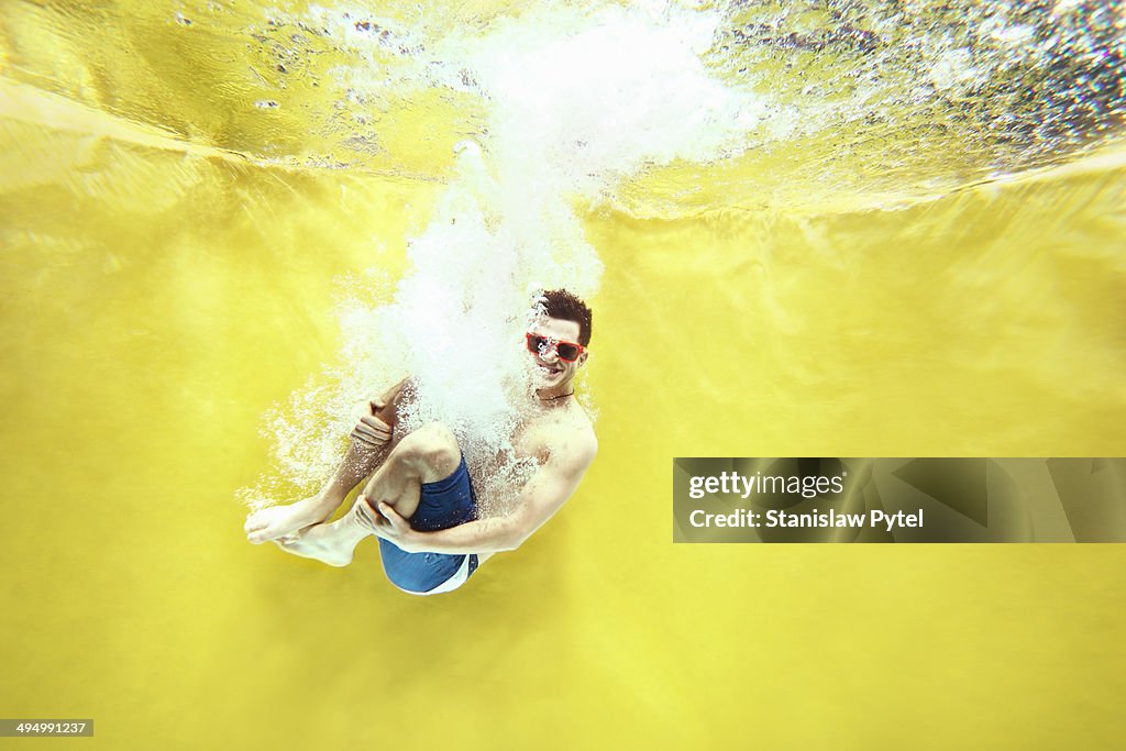 Boy jumping into water on yellow background