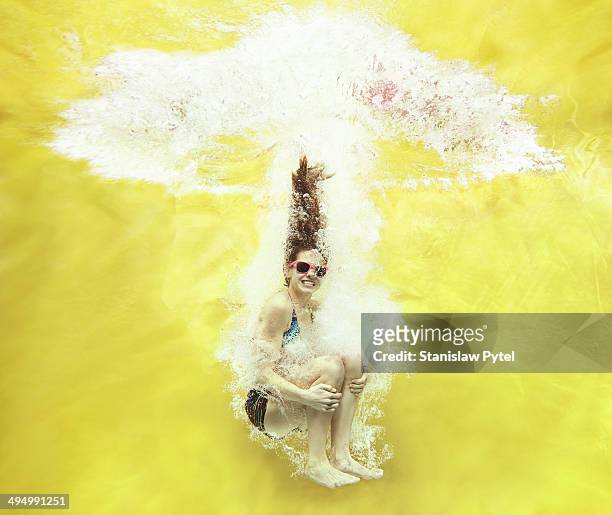 girl jumping into water on yellow background - cannonball diving stock pictures, royalty-free photos & images