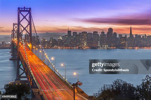 bay bridge and san francisco skyline at sunset - san francisco oakland bay bridge stockfoto's en -beelden