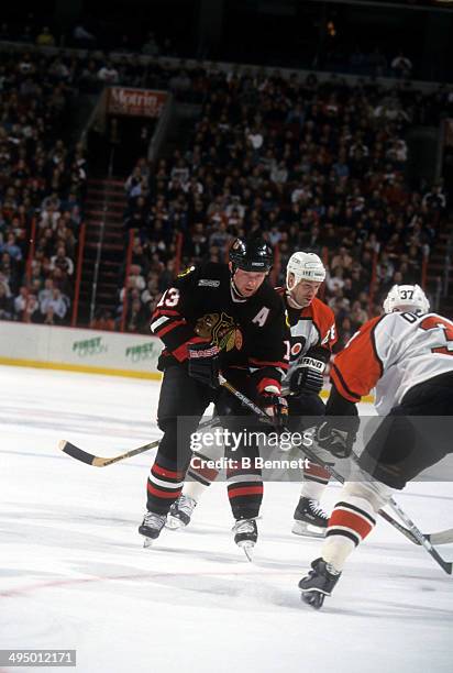 Alexei Zhamnov of the Chicago Blackhawks skates on the ice as Marc Bureau and Eric Desjardins of the Philadelphia Flyers defend on February 22, 2000...