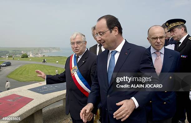 French President Francois Hollande listens to Arromanches mayor Patrick Jardin next to French Interior minister Bernard Cazeneuve as they tour the...