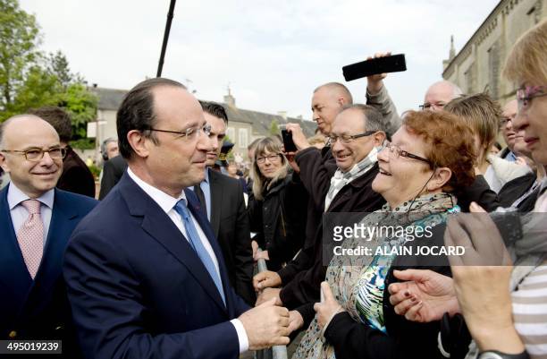French President Francois Hollande meets with people next to French Interior Minister Bernard Cazeneuve before a ceremony to honor WWII civilian...