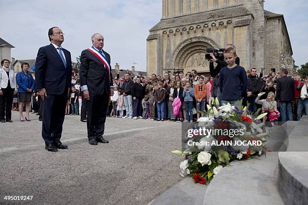 French President Francois Hollande and Trevieres' mayor Jean-Pierre Richard stand during a ceremony to honor WWII civilian casualties in Trevieres,...