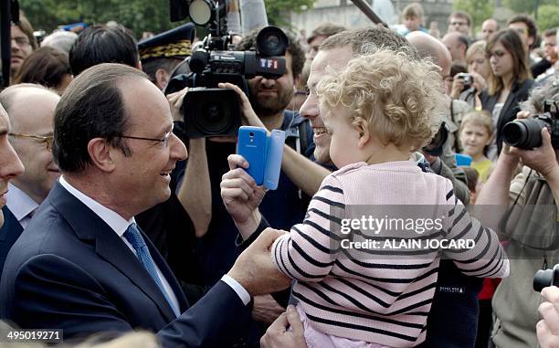 French President Francois Hollande shakes hands with a man and child before a ceremony to honor WWII civilian casualties in Trevieres, on June 1 as...