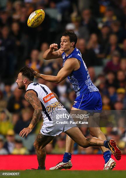 Scott Thompson of the Kangaroos handballs against Chris Masten of the Eagles during the round 11 AFL match between the West Coast Eagles and the...