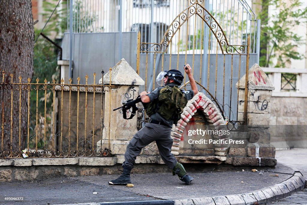 An Israeli soldiers hurls a tear gas bomb into a cemetary...