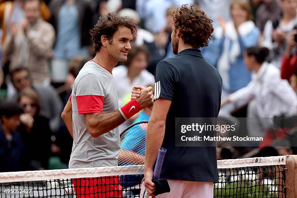 Roger Federer of Switzerland shakes hands with Ernests Gulbis of Latvia at the net following his defeat in their men's singles match on day eight of...