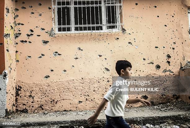 Boy walks past a bullet-riddled wall damaged during clashes between Turkish troops and Kurdish militants in the district of Sur in Diyarbakir,...