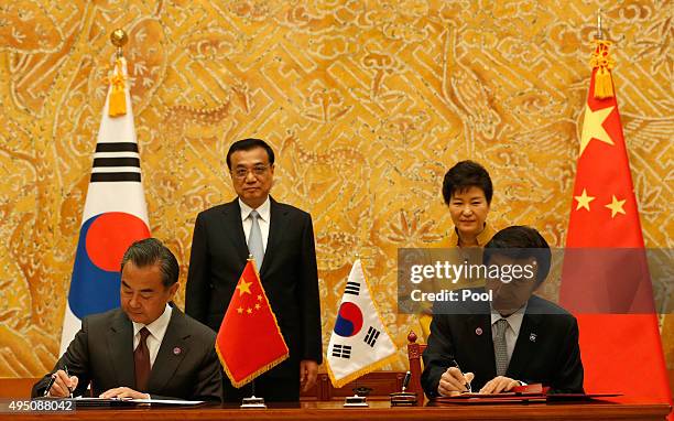 South Korea's Foreign Minister Yun Byung-Se and China's Foreign Minister Wang Yi sign a document as South Korean President Park Geun-Hye and Chinese...