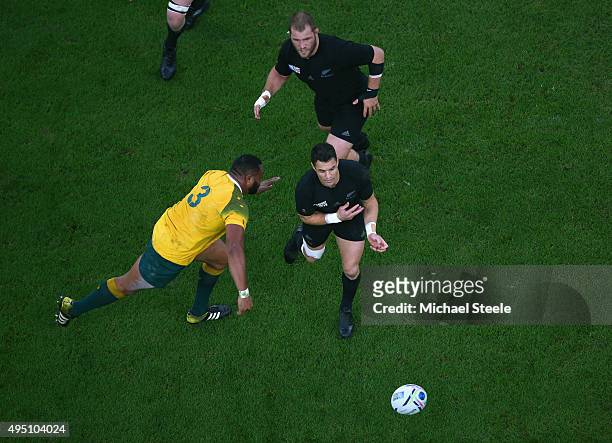 Dan Carter of the New Zealand All Blacks feeds a pass before taken a a high tackle by Sekope Kepu of Australia during the 2015 Rugby World Cup Final...