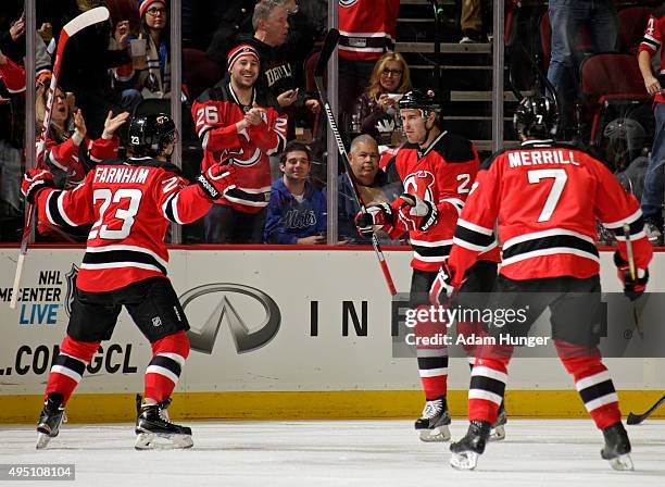 John Moore of the New Jersey Devils celebrates with Bobby Farnham and Jon Merrill after scoring a goal against the New York Islanders during the...