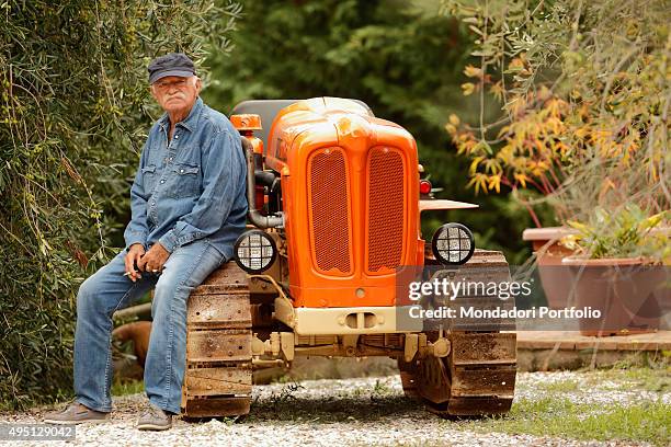 The singer-songwriter and musician Gino Paoli smoking a cigarette on a tracked tractor in a photocall shooted in his land in Maremma. Campiglia...